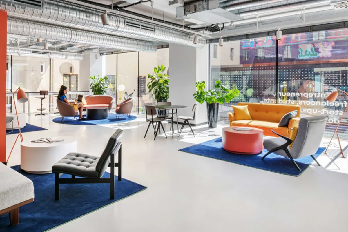 Lo spazio di coworking di The Social Hub, con divani colorati e piante